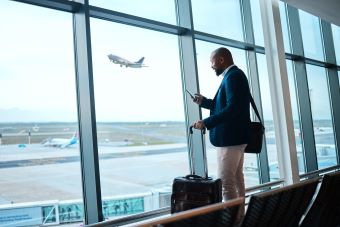 Branchenlösung Tourismus - Mann am Flughafen mit Smartphone